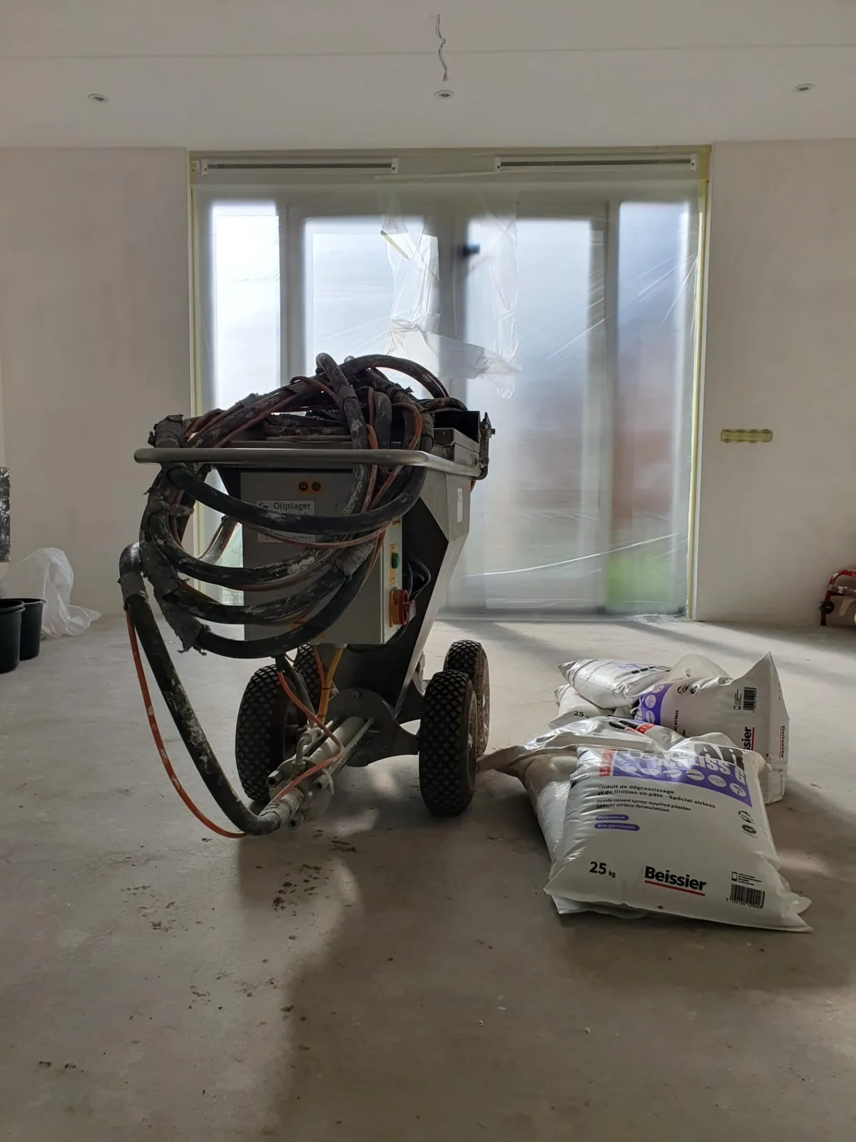 Spuitmachine voor het aanbrengen van dunpleister in een nieuwbouwwoning